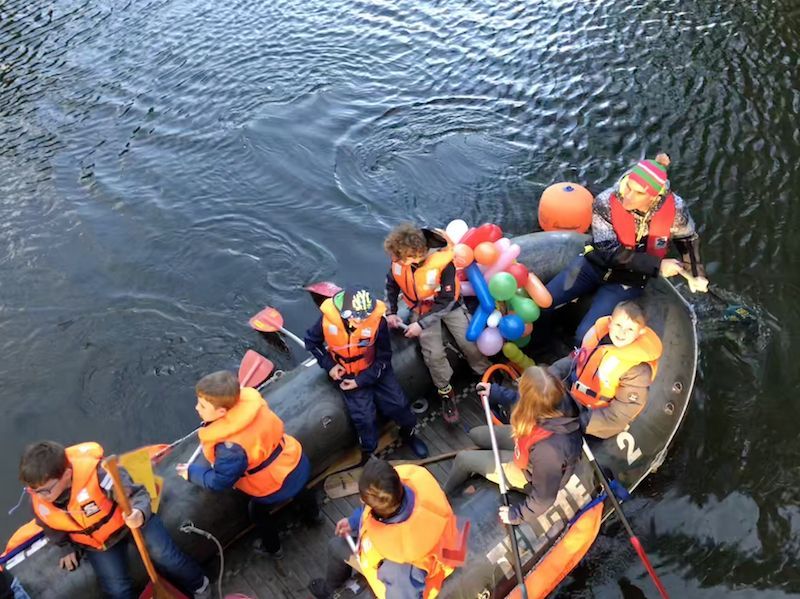 Ein fröhliches Gesicht blickt zum Brückengeländer empor. Mit acht Kindern saßen wir im Boot.