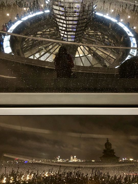 Wir sind inzwischen ein wenig höher gegangen in der Kuppel und blicken auf Berlin herunter. In der Scheibe gibt es eine spannende Spiegelung.